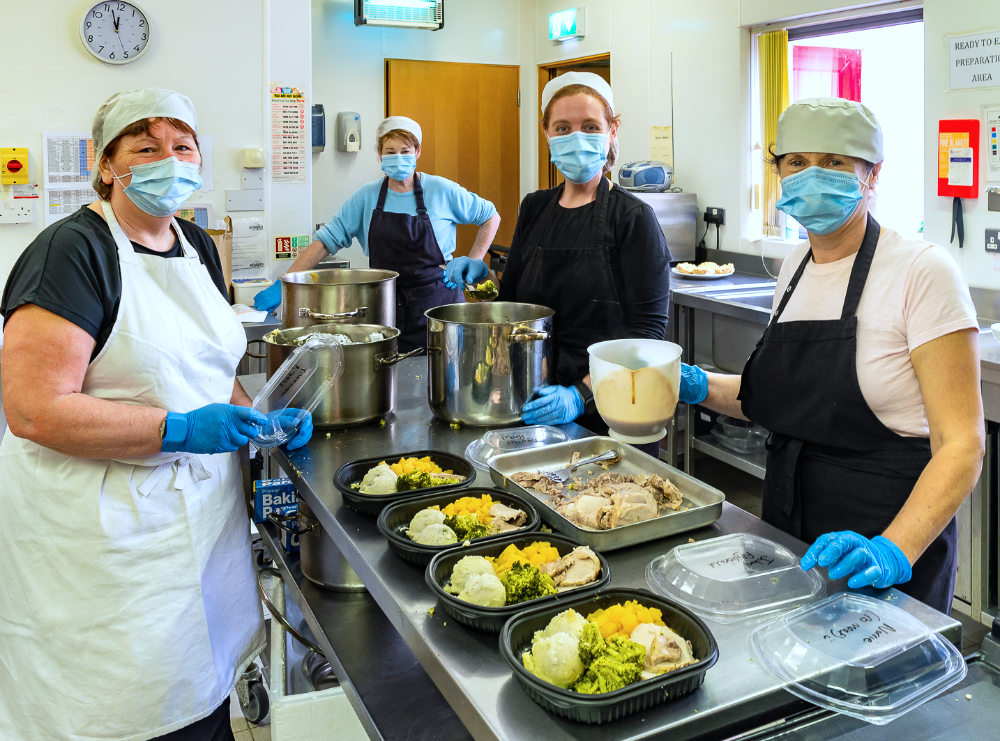 kitchen staff preparing meals on wheels dishes