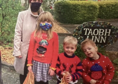 Woman and 3 children in Christmas clothes with bags